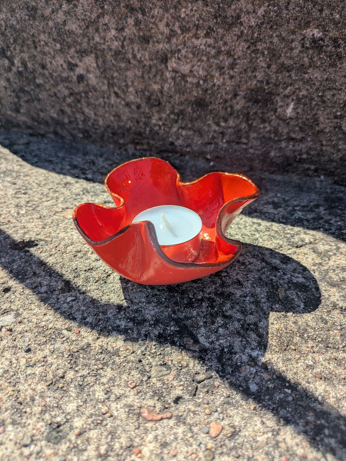 En röd blomformad skål med ett värmeljus