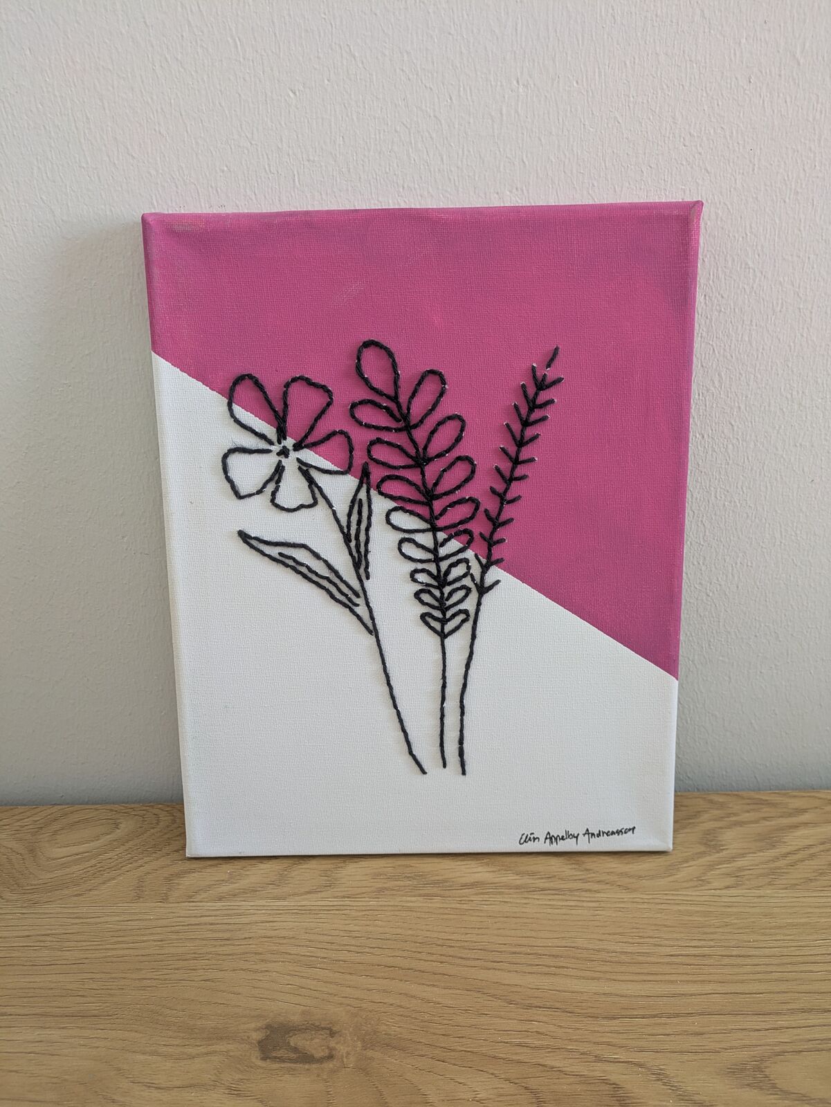 En kvist med små blommor mot rosa bakgrund